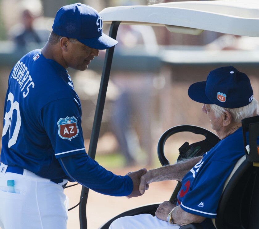 Dodgers Manager Dave Roberts, left, shakes hands with former Dodgers manager Tommy Lasorda during a spring baseball training workout on Feb. 28.