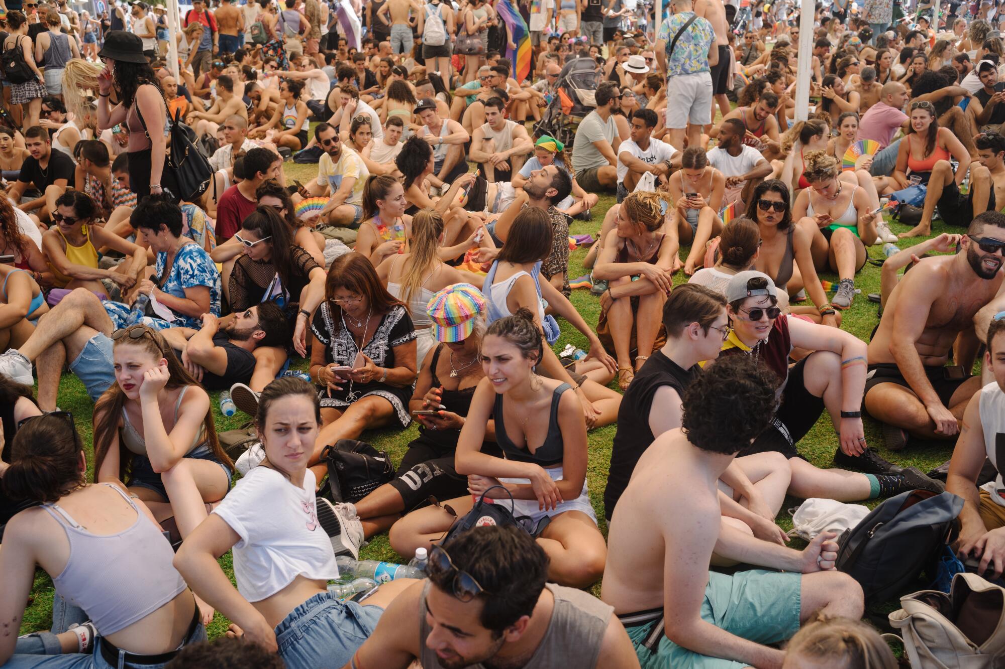 A large group of men and women sit on a grassy area