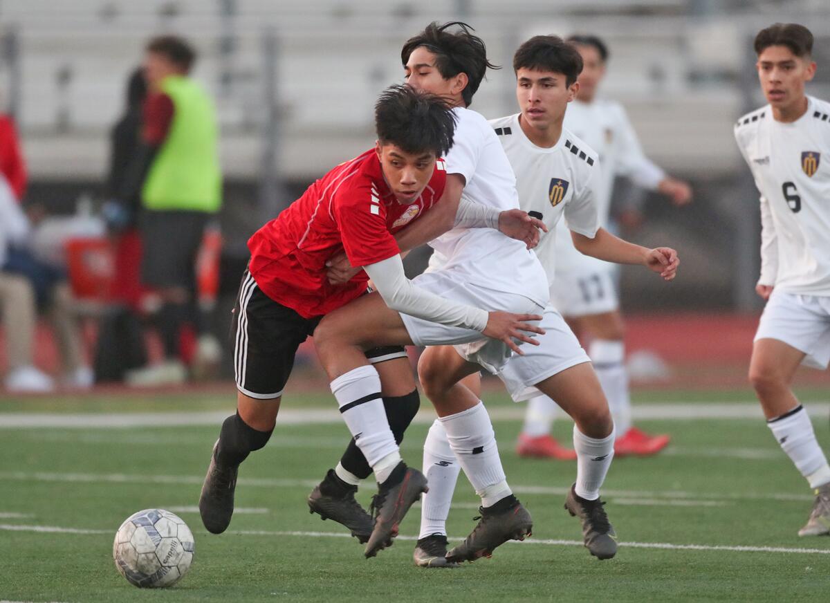 Ocean View's Jesse Camacho (4) drives into Marina's Taylen Vo (7) to take control of the ball during a boys' soccer match.