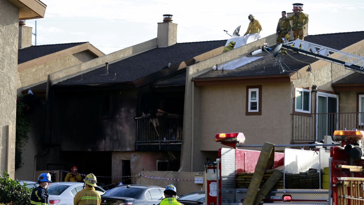 Firefighters work on the roof of a residence after the Hawthorne crash.