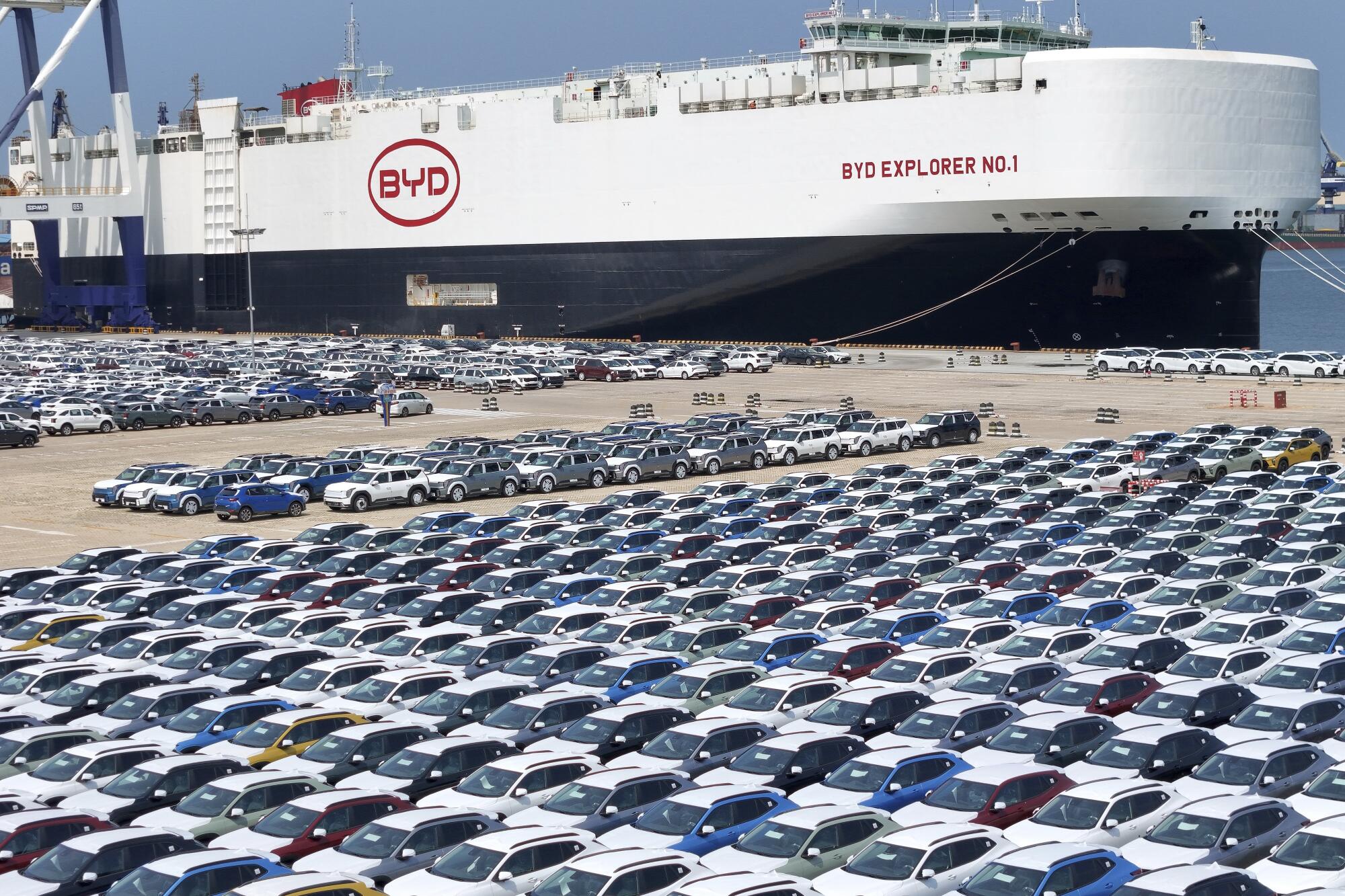 A ship is loading cars for export at a port.