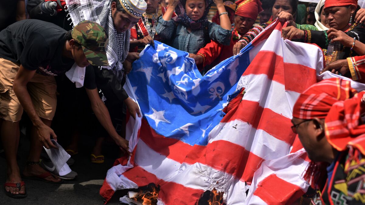 Members of an indigenous group and activists burn a U.S. flag during a protest Friday calling for the immediate pull-out of U.S. troops in the Philippines.