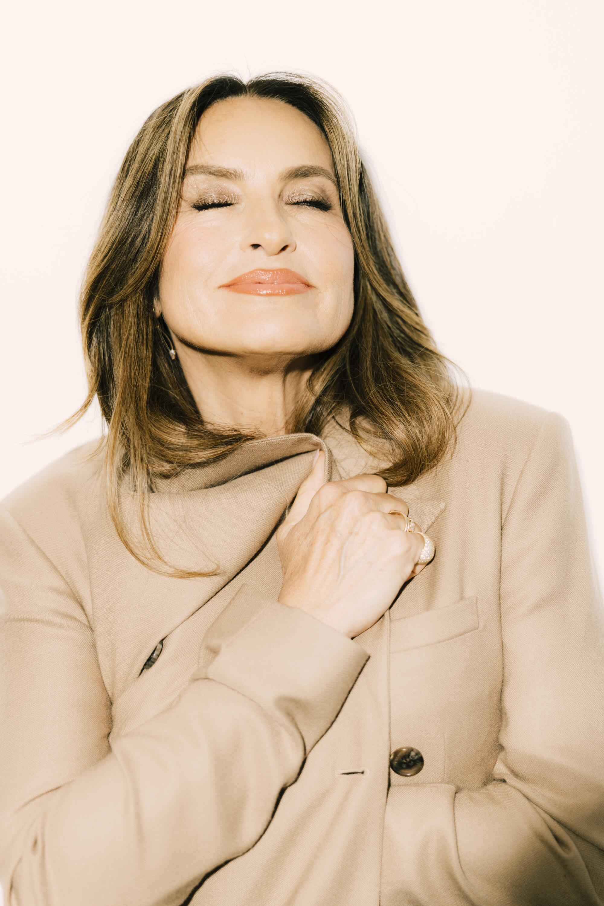 Mariska Hargitay smiles with her eyes closed with her arms wrapped around herself and her head tilted upward.