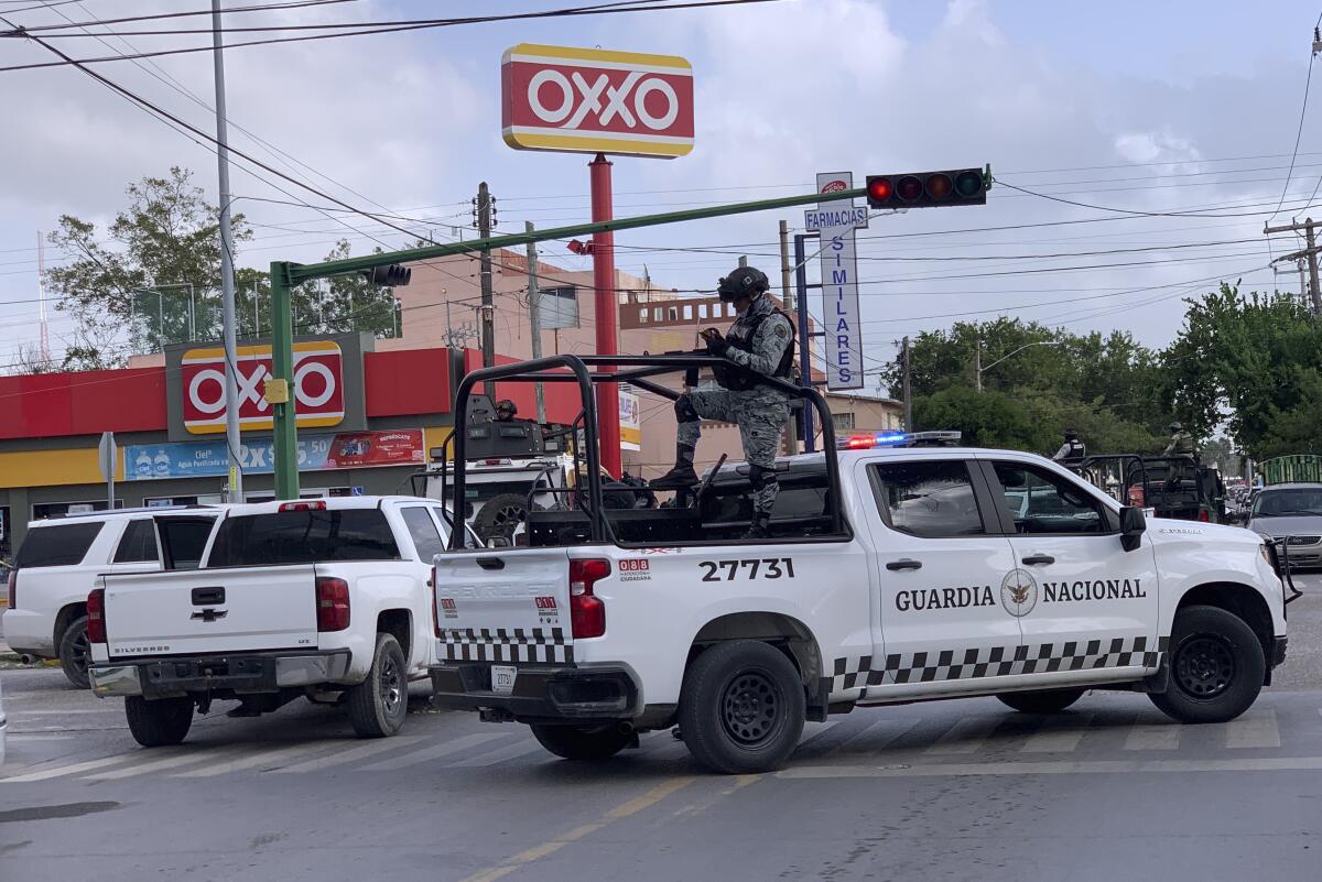 Soldados mexicanos montan guardia frente a una tienda de abarrotes Oxxo, 