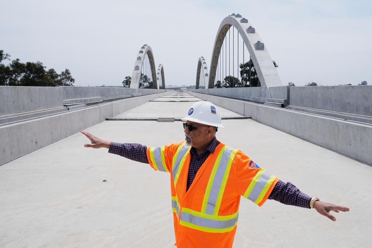 Garth Fernandez wears construction gear and speaks with his arms out.