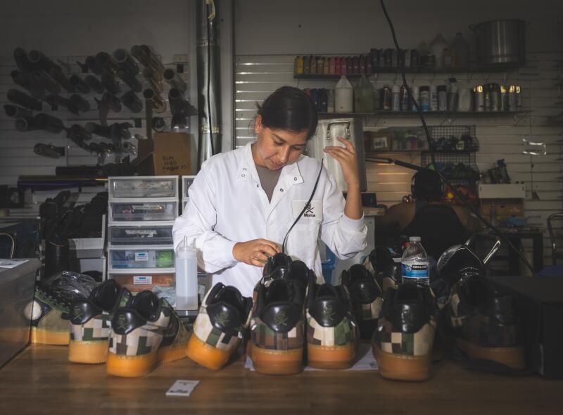 Mirna Lubiano, a quality control specialist, inspects sneakers.