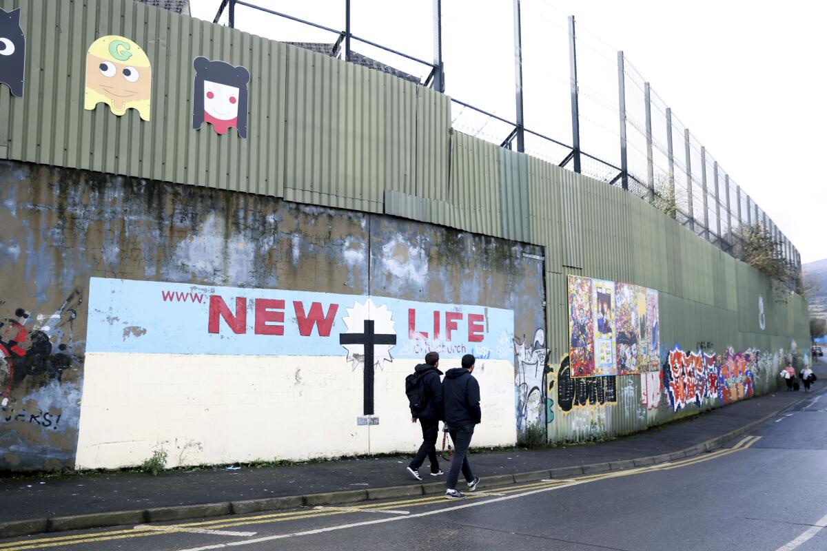 Tourists walk by the peace wall in west Belfast.
