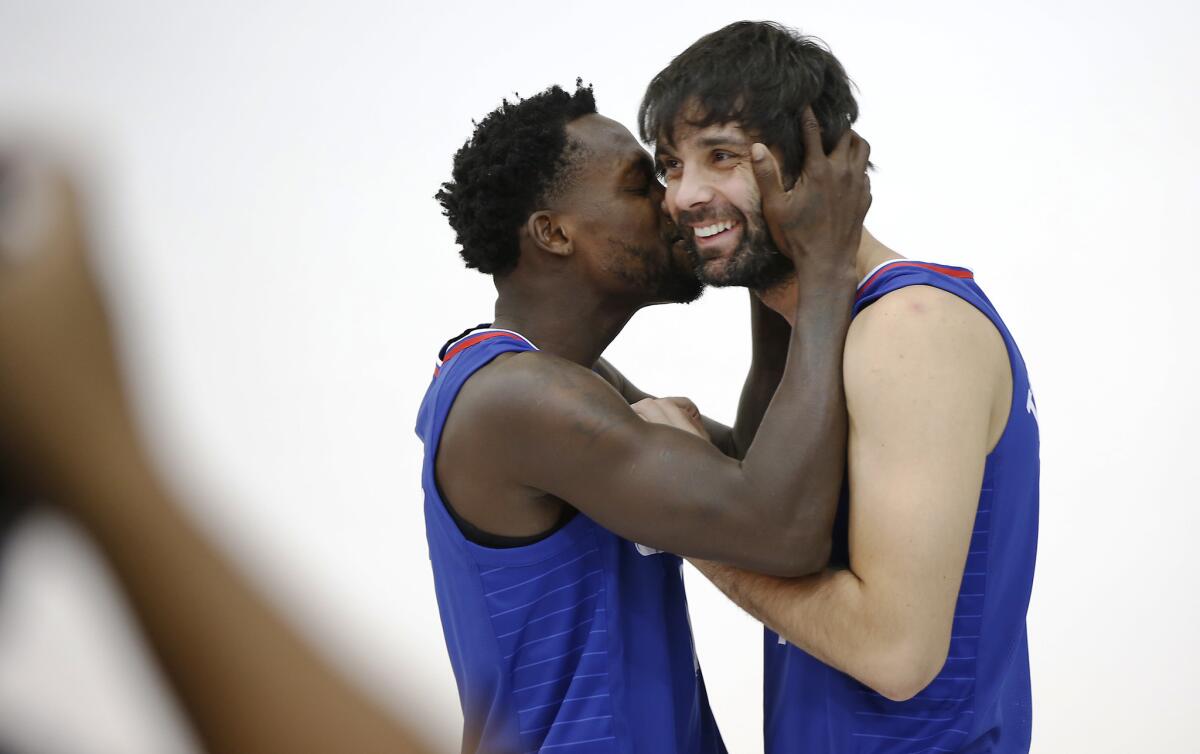 Patrick Beverley, left, spontaneously kisses teammate Milos Teodosic as they pose for photos during Clippers media day.