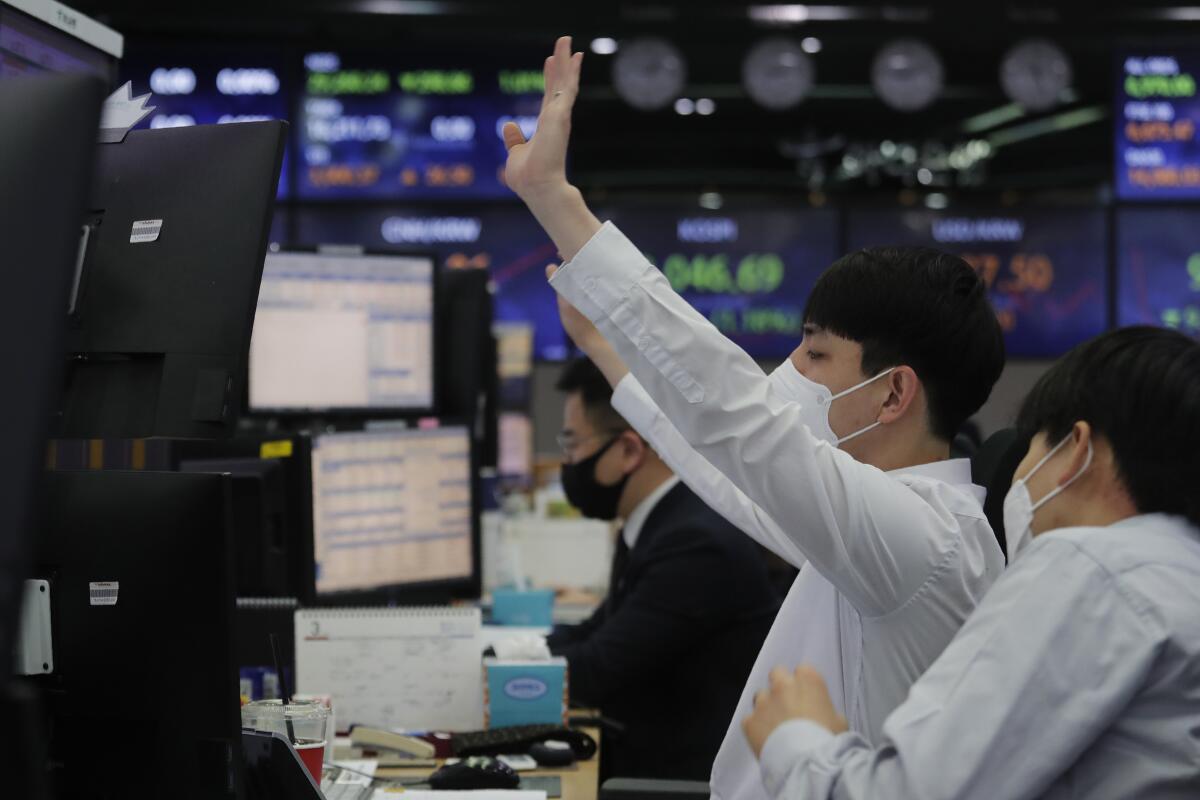 A currency trader gestures at the foreign exchange dealing room of the KEB Hana Bank headquarters in Seoul, South Korea, Thursday, March 4, 2021. Asian shares fell Thursday, tracking a decline on Wall Street as another rise in bond yields rattled investors who worry that higher inflation may prompt central banks to raise ultra-low interest rates. (AP Photo/Ahn Young-joon)
