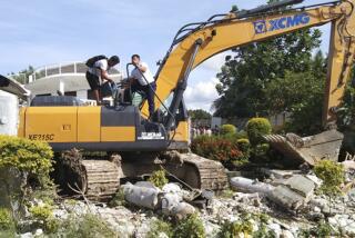 Men refuel a backhoe being used to sift through the rubble after a strong earthquake in central Philippines on Tuesday.