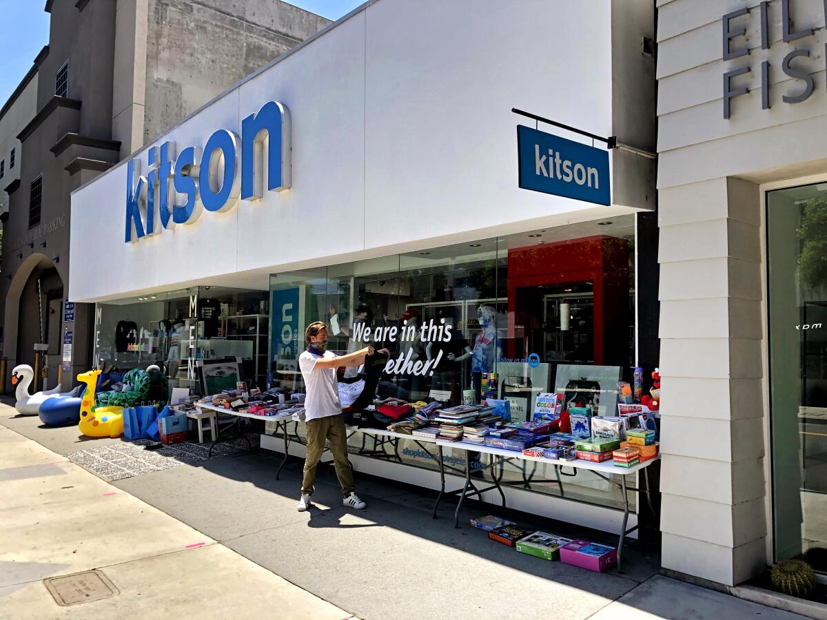 Kitson employee Tom Ernst rearranges clothing and other merchandise on folding tables outside the storefront