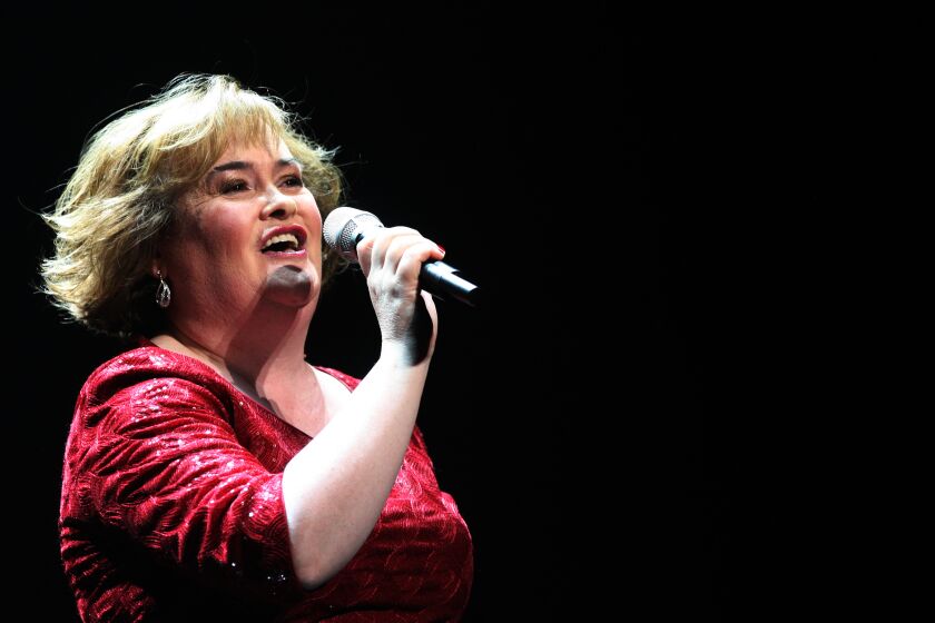 Susan Boyle tilts her head back while singing into a microphone