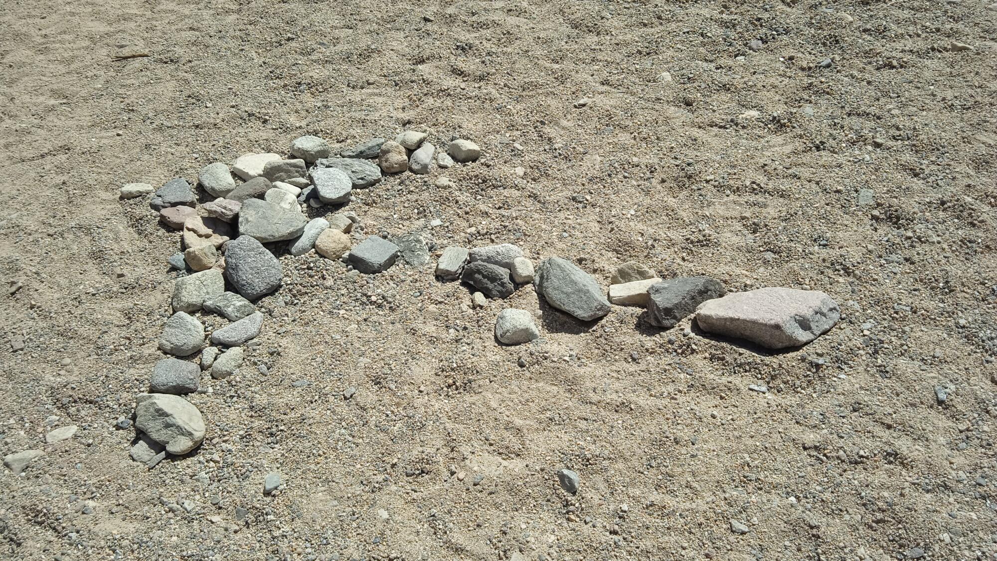 An arrow made of stones rests in the desert sand