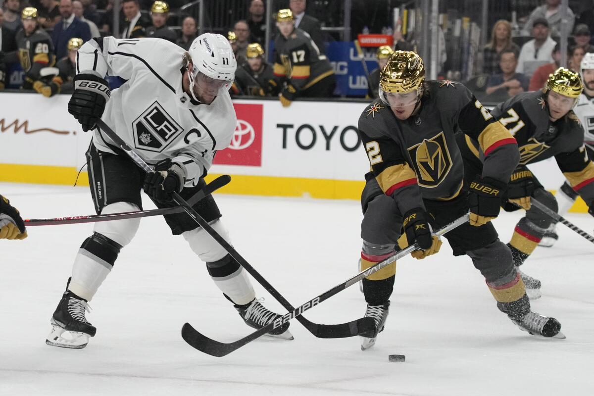 Kings forward Anze Kopitar passes around Vegas Golden Knights defenseman Zach Whitecloud.