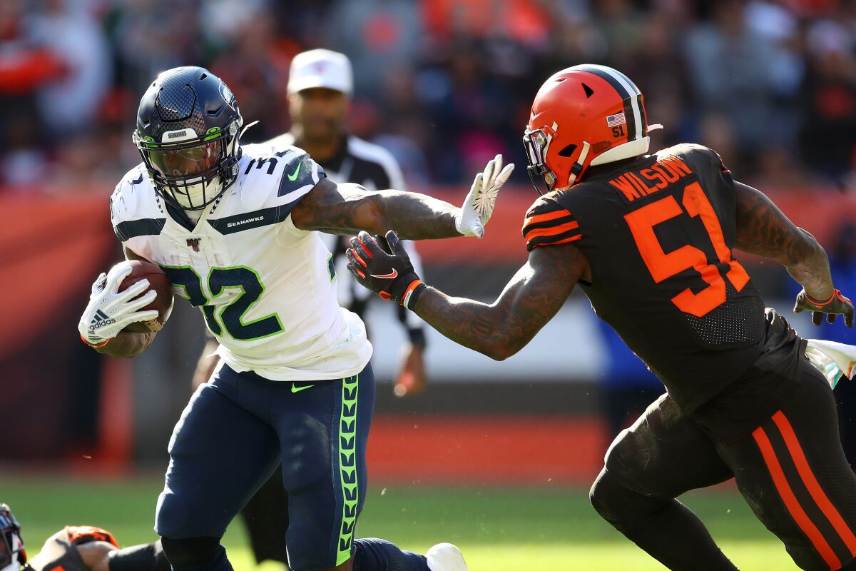 Seattle Seahawks running back Chris Carson, left, battles for yards against Cleveland Browns linebacker Mack Wilson during the fourth quarter of Sunday's game.