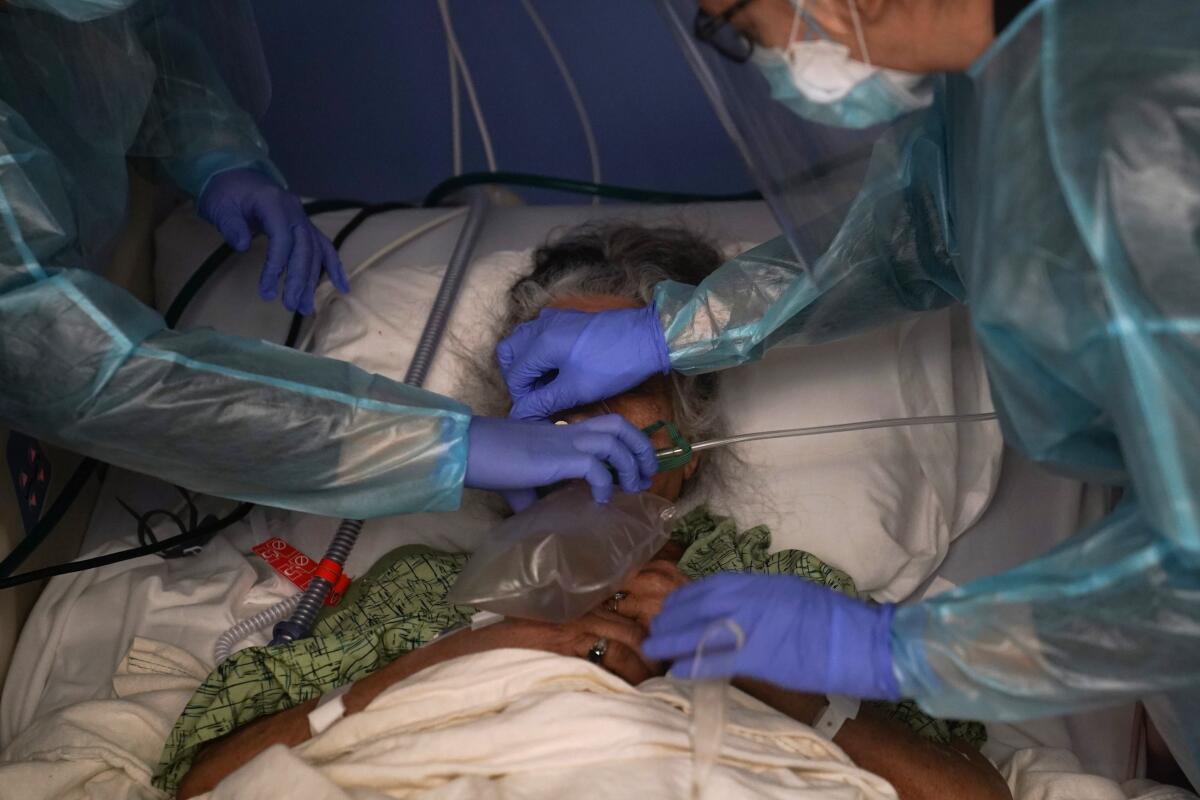 Two nurses put a ventilator on a patient in a COVID-19 unit in Orange, Calif. 