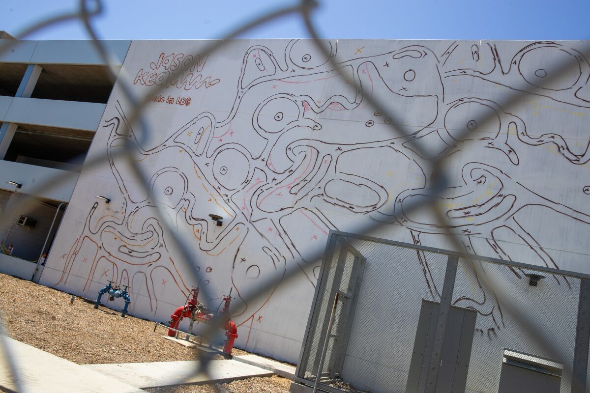 A mural by Jason Keam in progress on the east side of West Broadway Parking