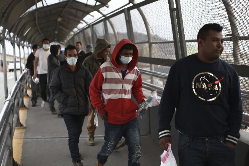 FILE - In this Saturday, March 21, 2020 file photo, Central American migrants seeking asylum, some wearing protective face masks, return to Mexico via the international bridge at the U.S-Mexico border that joins Ciudad Juarez and El Paso. Mexico and the U.S. are restricting travel over their busy shared border as they try to control the spread of the coronavirus pandemic. (AP Photo/Christian Chavez)