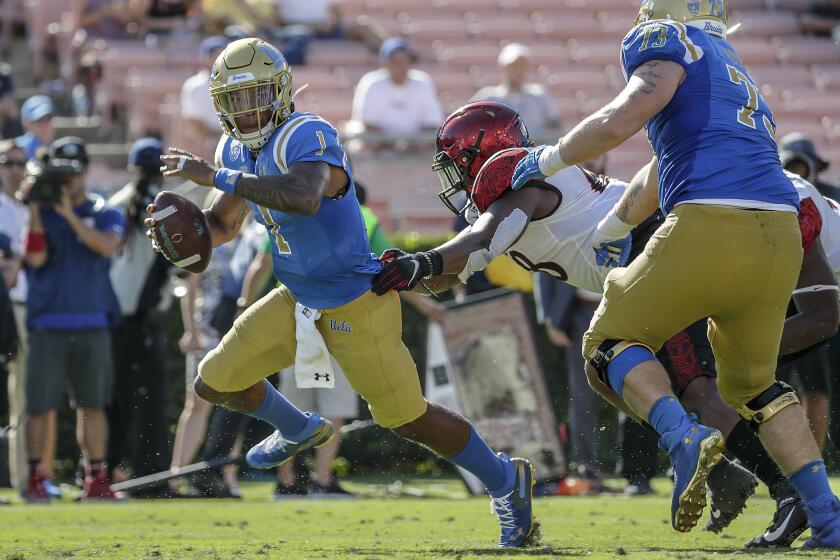 UCLA quarterback Dorian Thompson-Robinson runs away from the pressure by defensive end Myles Cheatum.