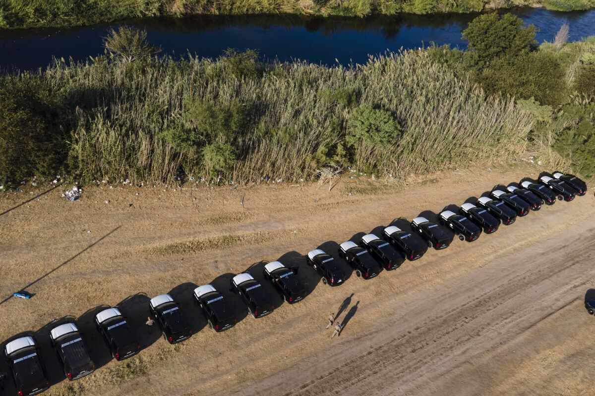 A line of Texas Department of Safety vehicles lines the bank of the Rio Grande.