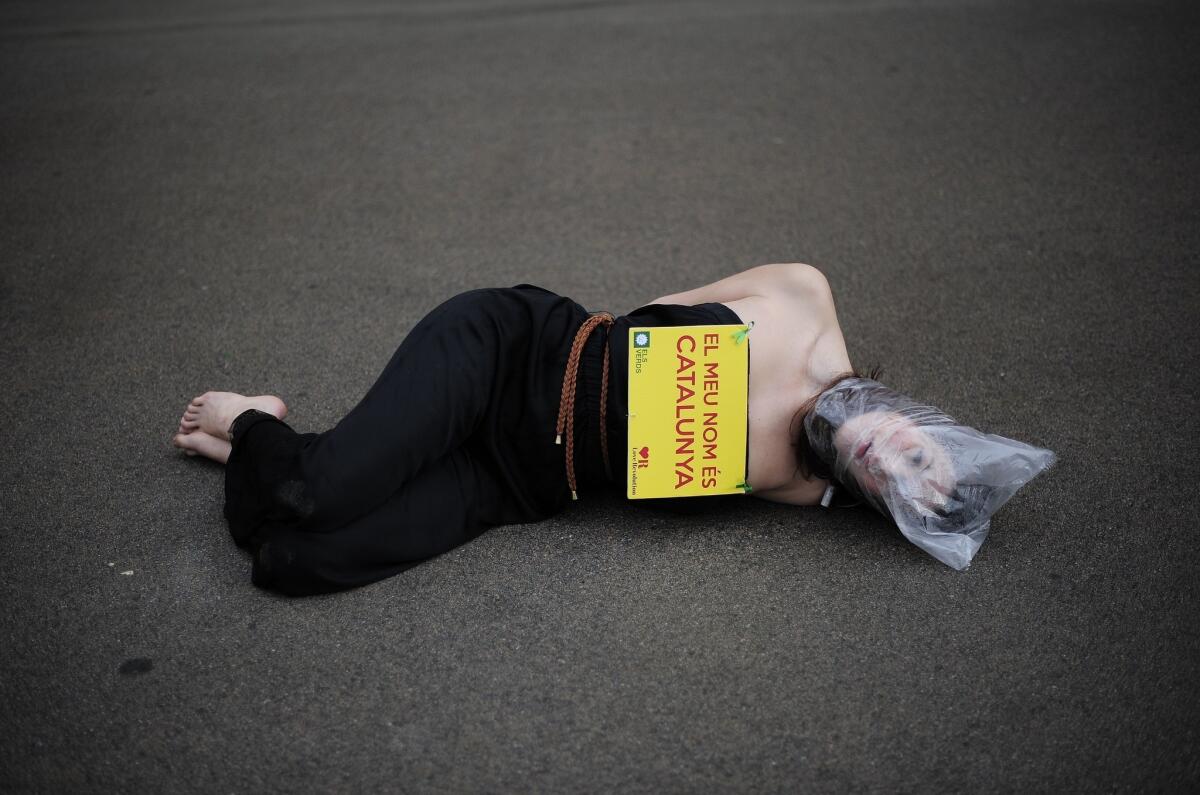 An pro-independence protester with a plastic bag on her head and a banner reading "My name is Catalonia" lies on the ground outside Catalonia's parliament in Barcelona during a vote on a petition to the national parliament to allow a referendum on independence.