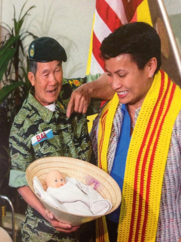 A family album photo shows Bao Tran and Kimberly Mitchell at their reunion in 2013. He gave her a conical hat with a doll inside. "This is how I found you," he told her.