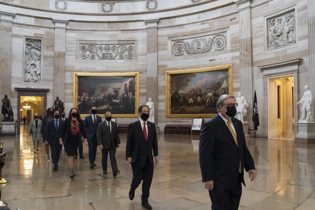People walk in a line through the Capitol Rotunda.