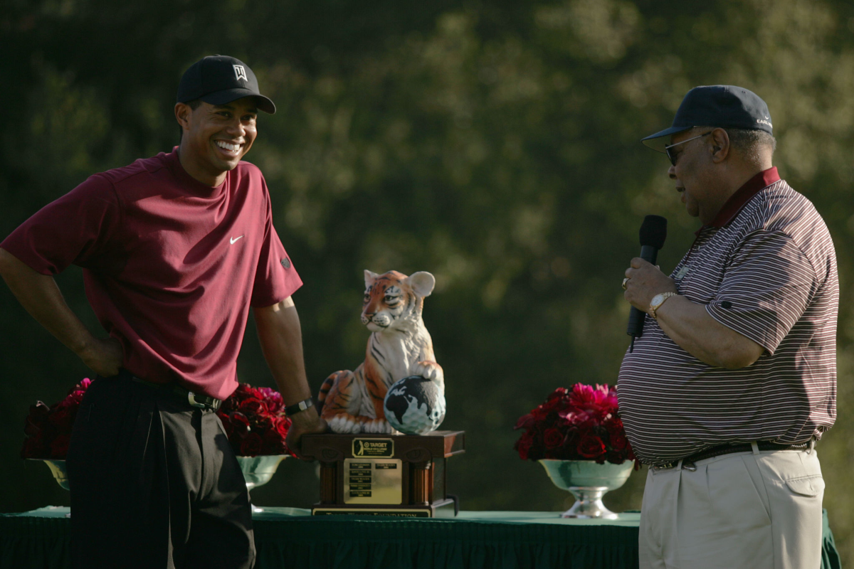 Tiger Woods laughs as his father Earl Woods presents him with a trophy.