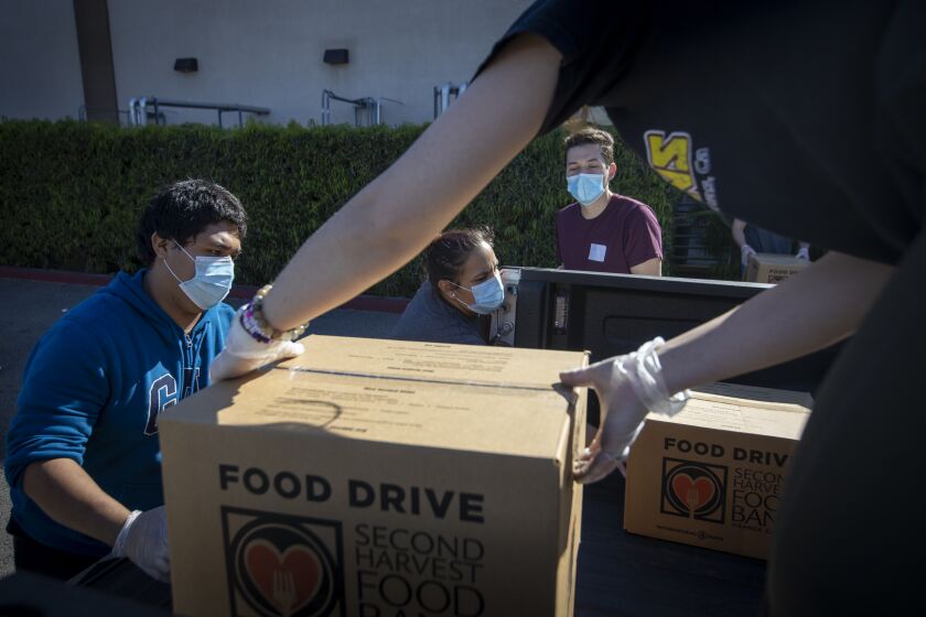 IRVINE, CA -- WEDNESDAY, APRIL 1, 2020: From left: Jose Secundino, Shavonne Budnik, Andres Quintana, and Madison Amador, who are all recently hired Second Harvest Food Bank of Orange County temporary employees, and have been laid off from restaurant jobs due to the coronavirus pandemic, load boxes of food into volunteers' trucks that will be delivered to local senior centers in Orange County. Photo taken at Second Harvest Food Bank at the Orange County Great Park in Irvine, CA, on April 1, 2020. (Allen J. Schaben / Los Angeles Times)