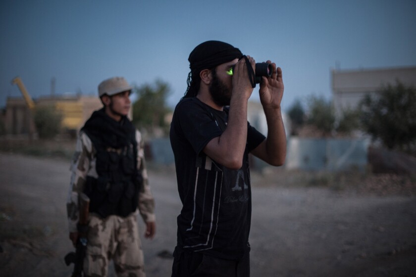 A member of the Islamist Syrian opposition group Ahrar al Sham uses a night-vision scope to monitor a position in the countryside in Raqqah province in August 2013.