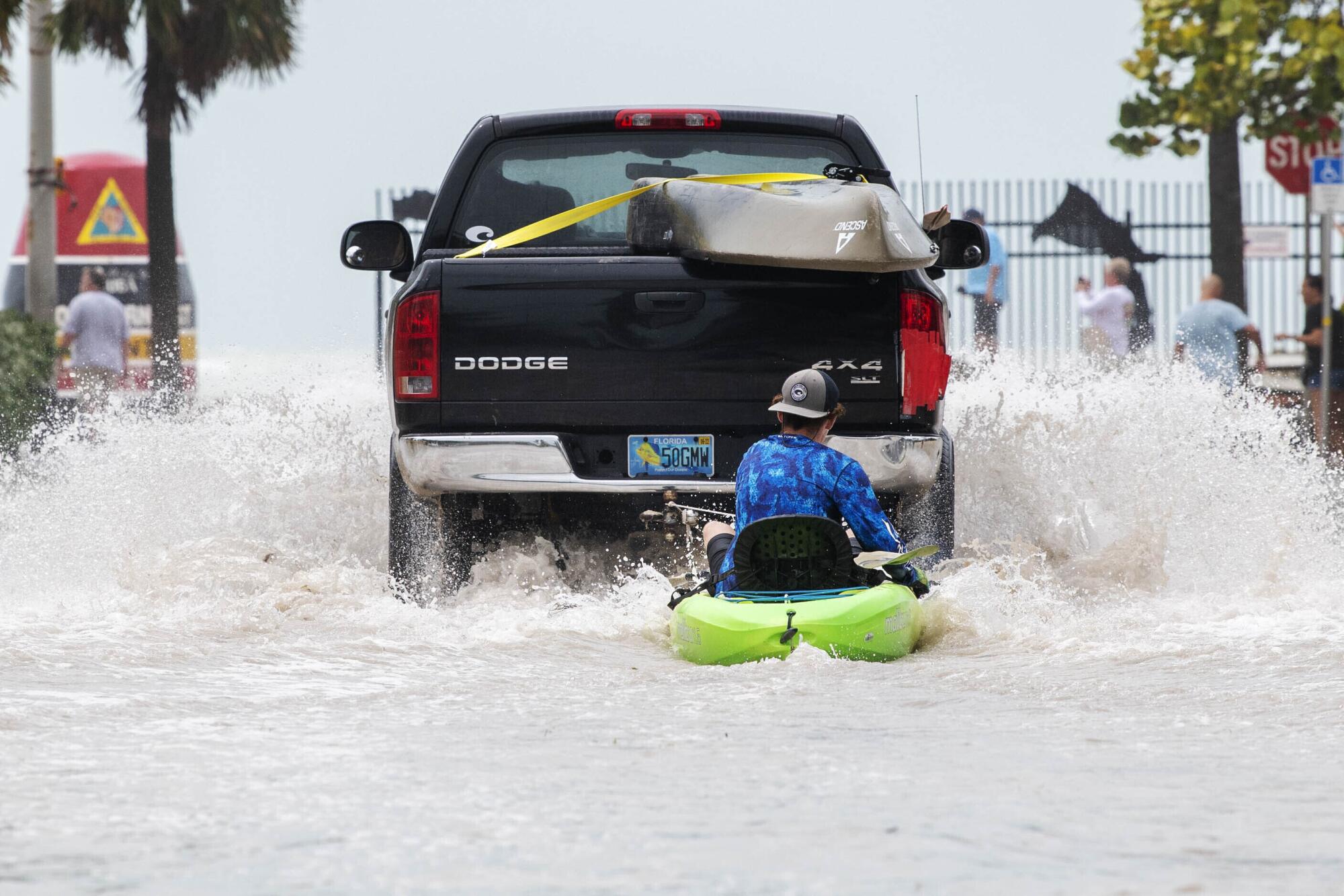 A truck pulls a man on a kayak in floodwater.