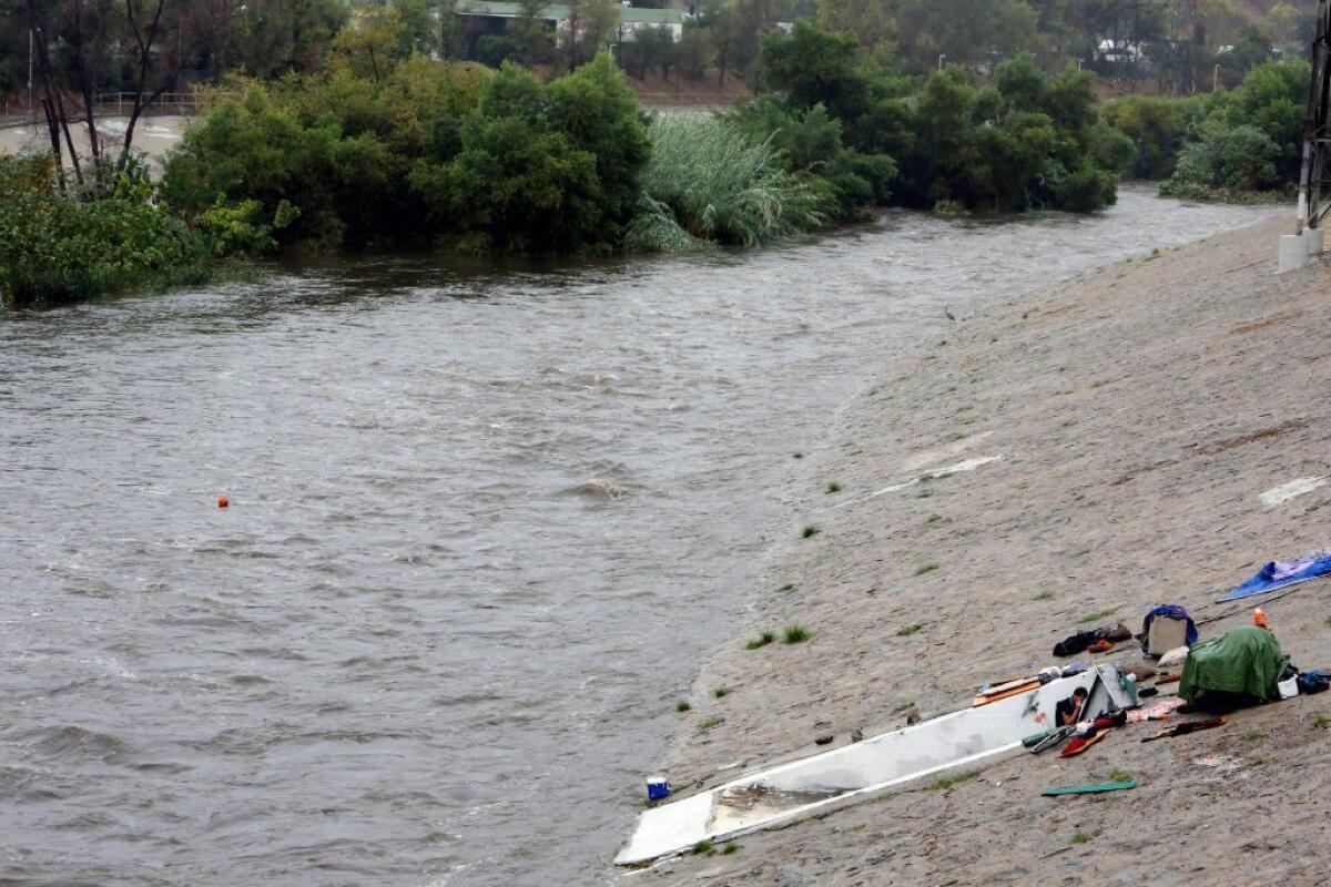 A man clears his belongings from the banks of the Los Angeles River on Tuesday as a record-breaking storm slammed parched Southern California.