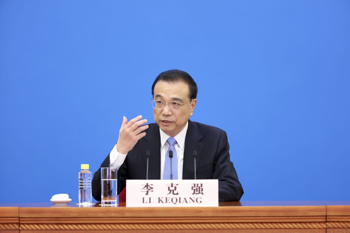 In this photo released by China's Xinhua News Agency, Chinese Premier Li Keqiang speaks during a press conference after the end of the closing session of China's National People's Congress (NPC) at the Great Hall of the People in Beijing, Friday, March 11, 2022. China's government hopes to generate as many as 13 million new jobs this year to help reverse a painful economic slowdown, the country's No. 2 leader said Friday. (Ding Haitao/Xinhua via AP)