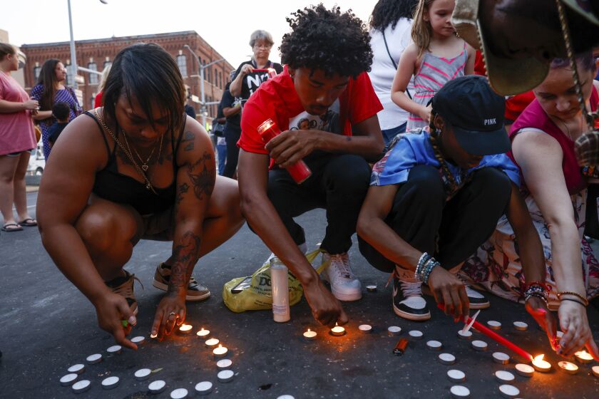 Branden Colvin Jr., center, lights candles for his father, Branden Colvin Sr., with Devina Henderson, left, and Malia Rush, right, during a candlelight vigil for Colvin, Ryan Hitchcock and Daniel Prien, at the site of a building collapse, Sunday, June 4, 2023, in Davenport, Iowa. The three men had been missing since the partial collapse of the apartment building on May 28. Colvin has since been confirmed to have died in the collapse. (Nikos Frazier/Quad City Times via AP)