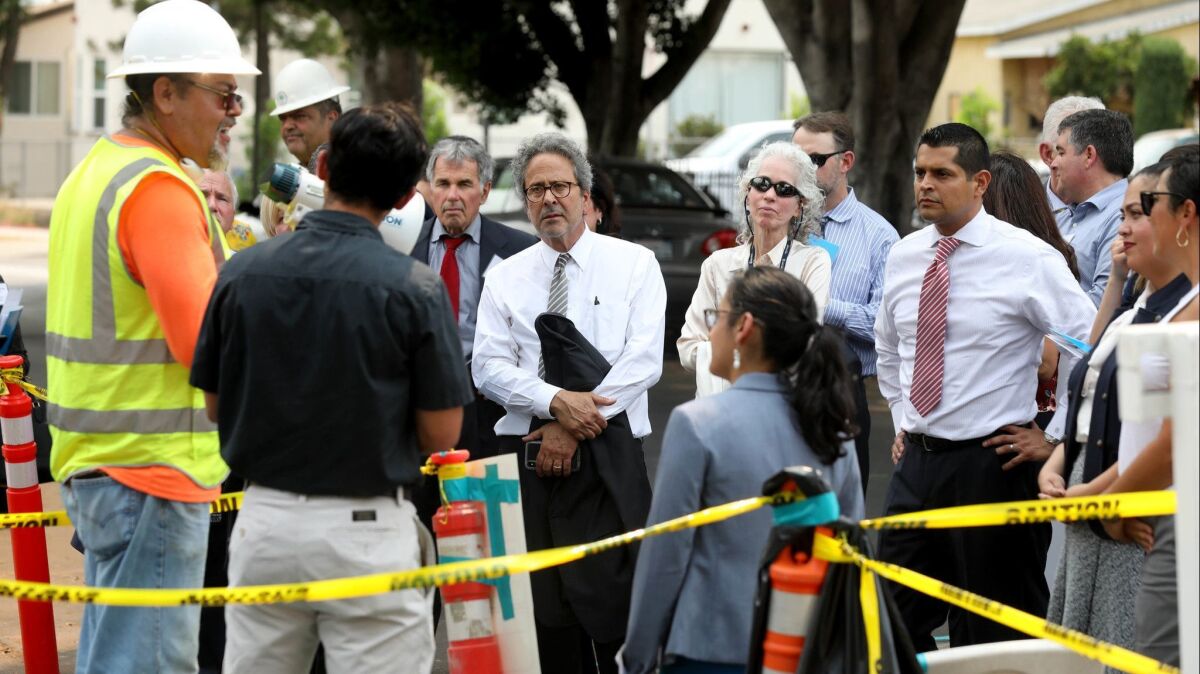 Assemblyman Richard Bloom (D-Santa Monica), center facing, Barbara Ferrer, director of the L.A. County Department of Public Health, and Assemblyman Miguel Santiago (D-Los Angeles), on a bus tour for state and local government officials, visit a house where soil is being removed.