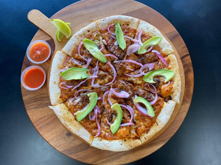 L.A. Birria Pizza's ahogada pizza with carnitas, beans, two ahogada sauces, pickled onions and avocado.