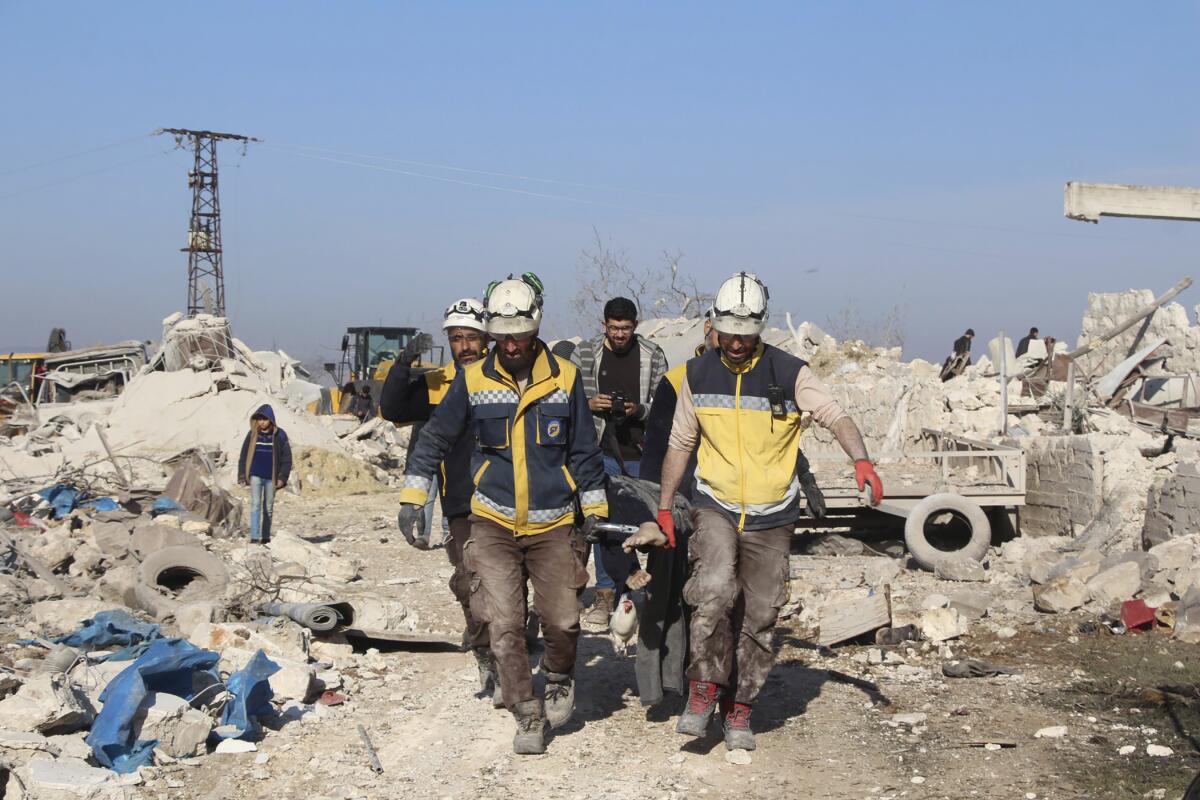 Syrian workers carry a victim following airstrikes in Maaret Musreen village on Thursday.