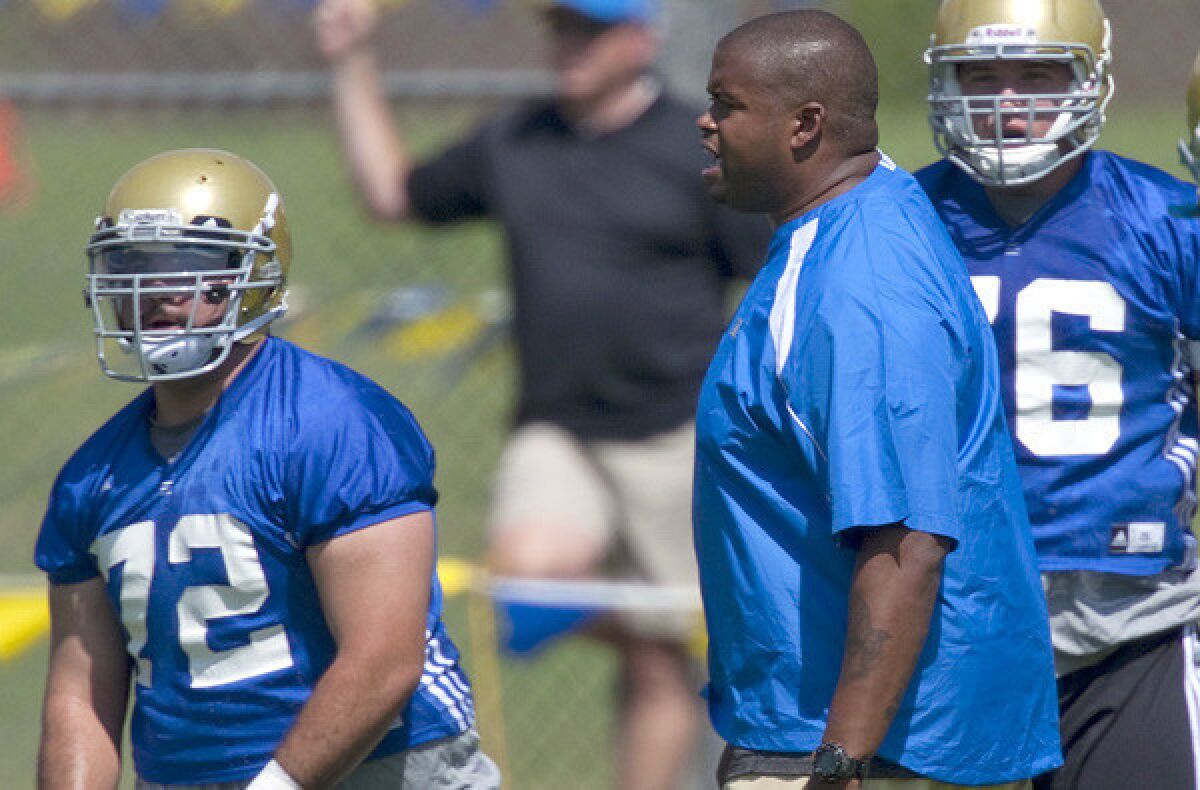 Offensive line coach Adrian Klemm works with Bruins players during summer camp.
