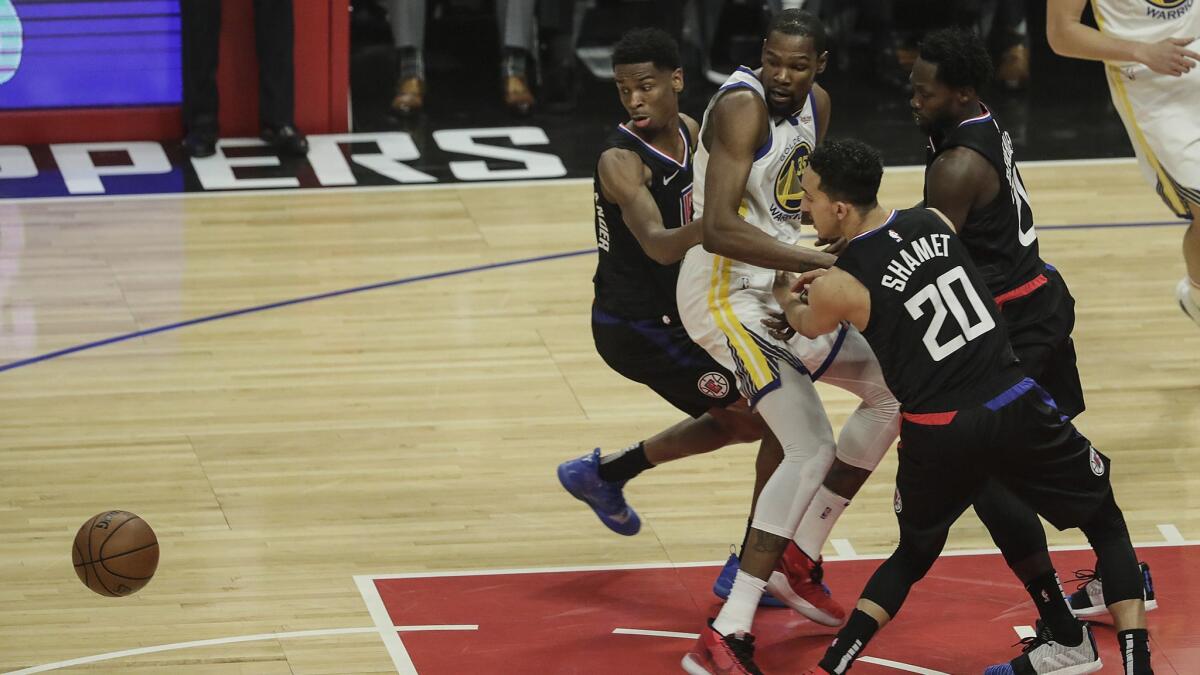 Clippers defenders knock the ball from Warriors forward Kevin Durant during the first quarter.