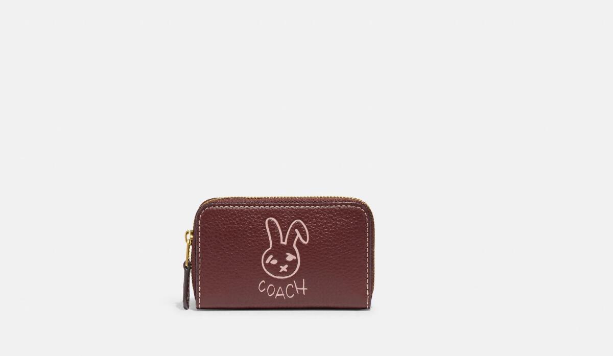 A zip-around leather card case decorated with the image of a rabbit and the word Coach