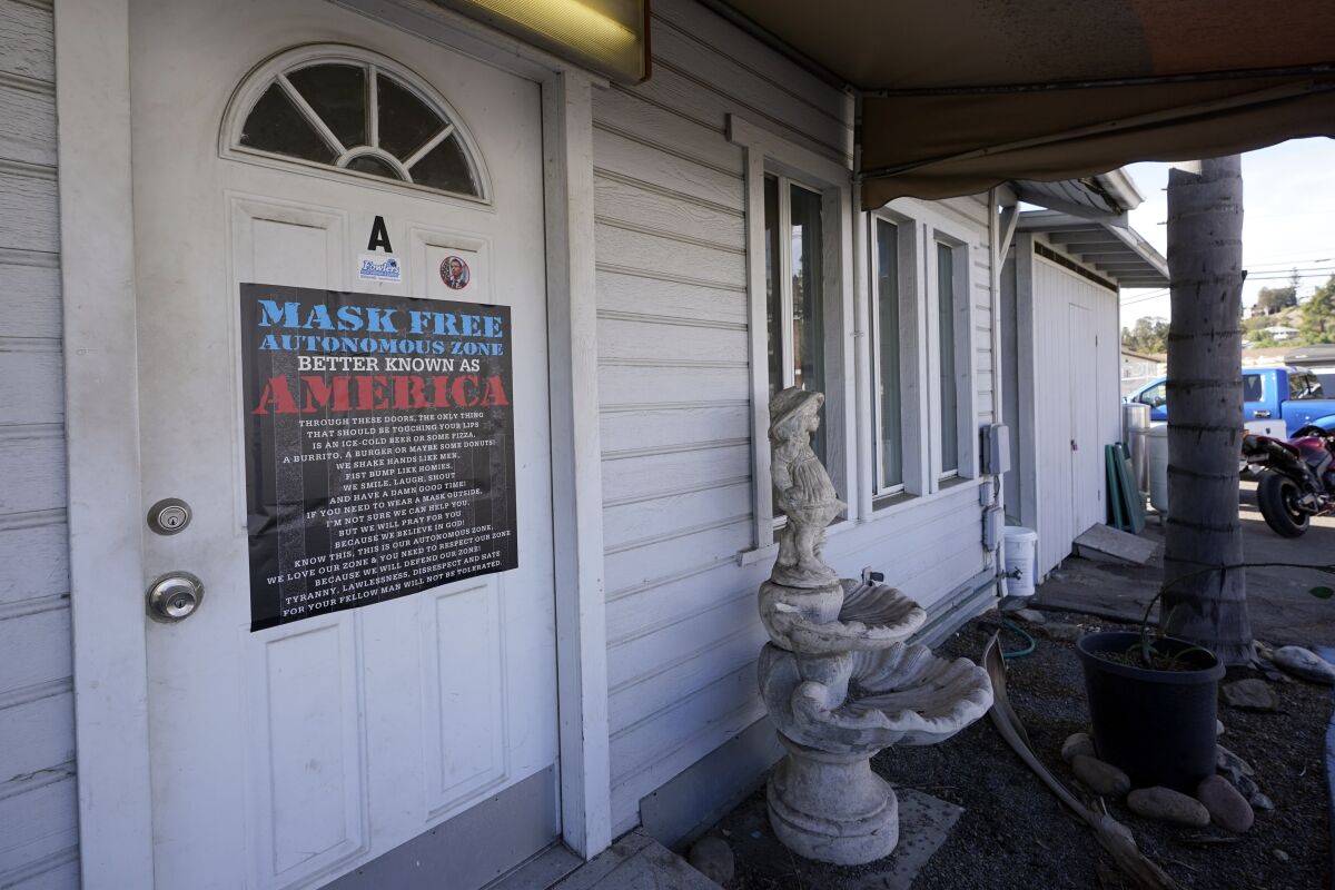 A sign on the door of a building says "Mask Free Autonomous Zone, Better Known as America"