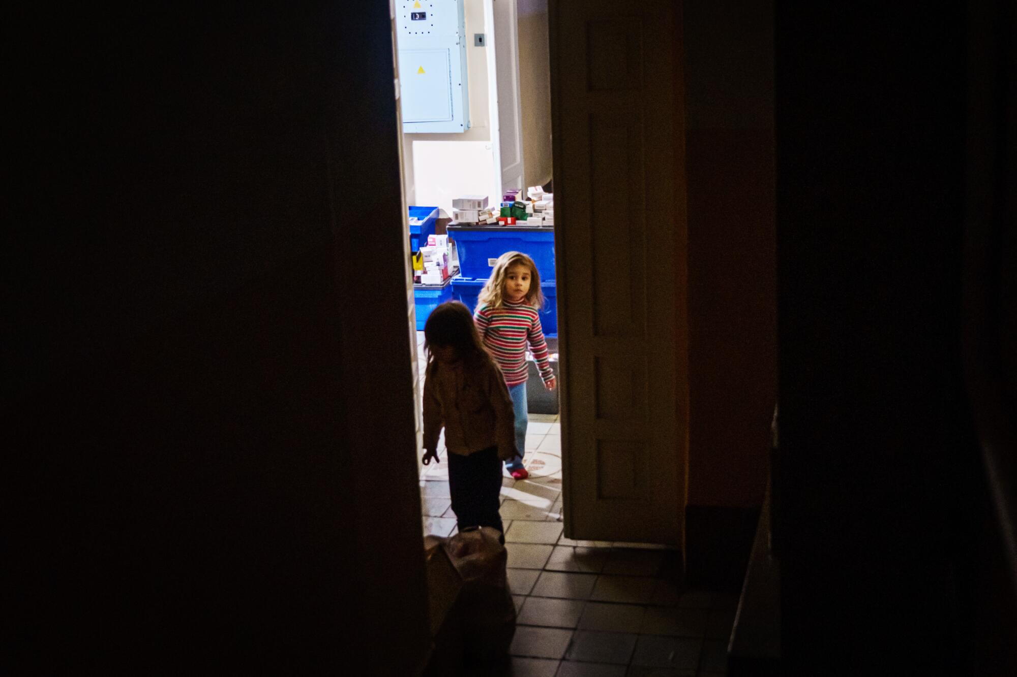 Two young girls are seen in a lighted doorway.
