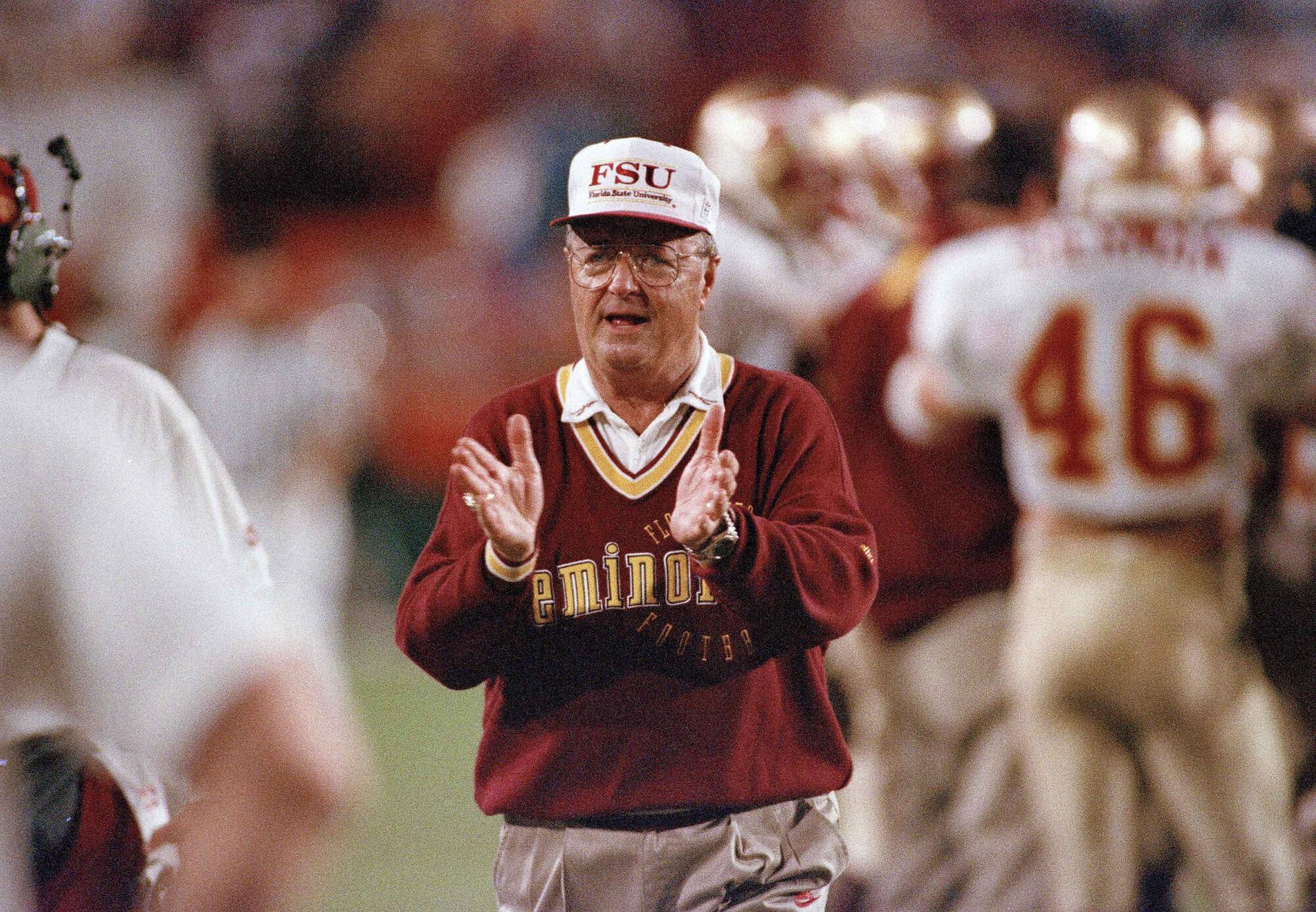 Bobby Bowden walks along the sidelines clapping.