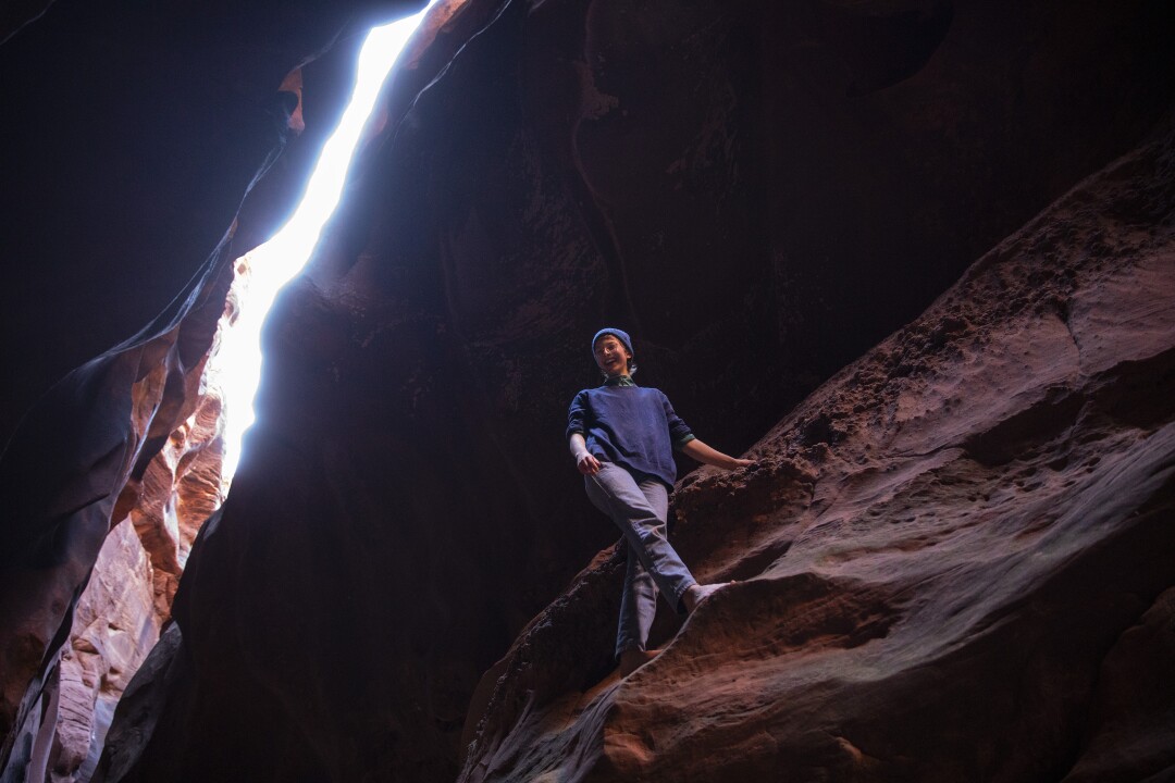 A hiker pauses on a canyon wall inside Buckskin Gulch.