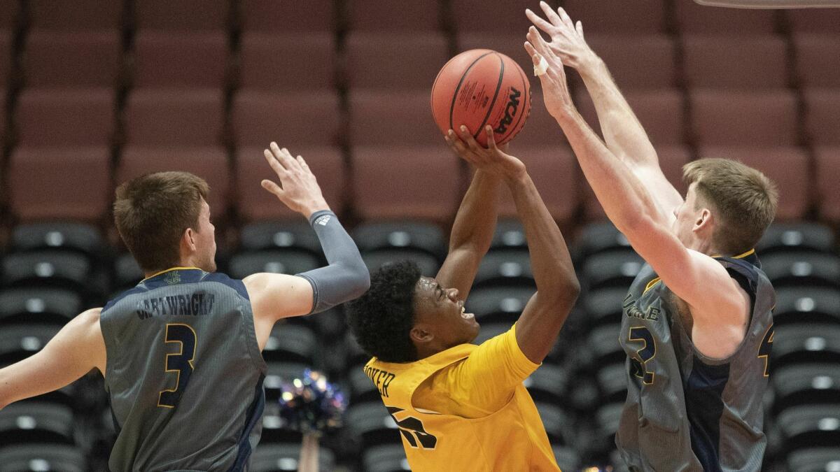 Long Beach State guard Deishuan Booker, center, shoots between UC Irvine guard Robert Cartwright, left, and forward Tommy Rutherford during the first half at the Big West men's tournament in Anaheim on Friday.