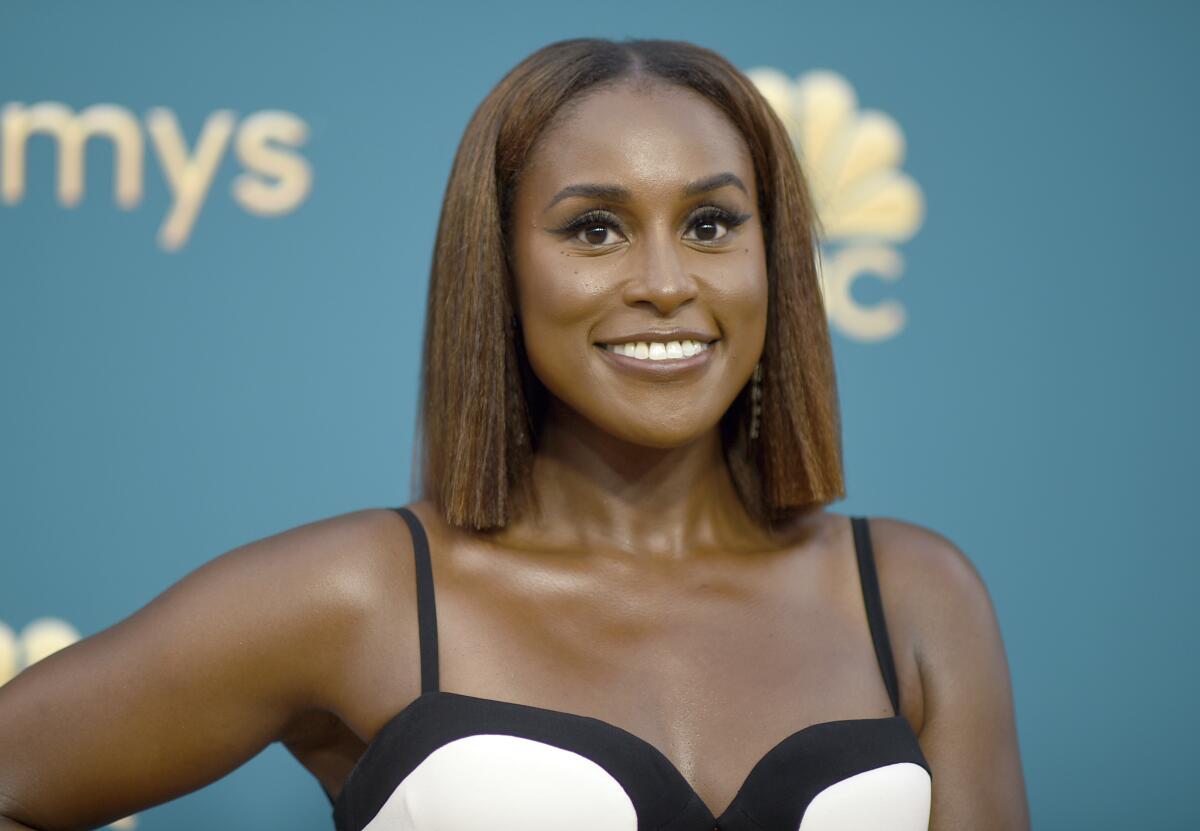 Issa Rae smiling in a black and white thin-strapped gown
