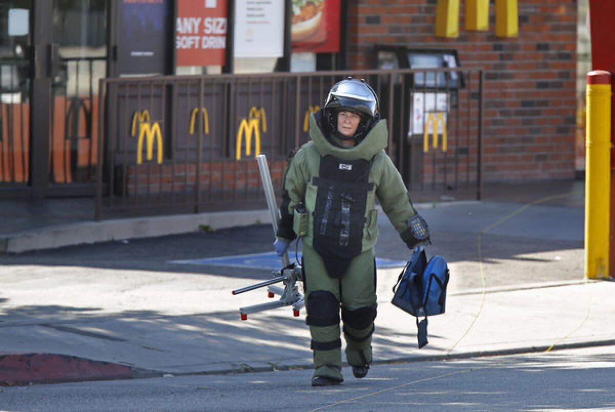 A Los Angeles County Sheriff's Bomb Squad member carries an empty backback from a McDonalds restaurant near the campus of Cal State L.A. on Thursday afternoon.