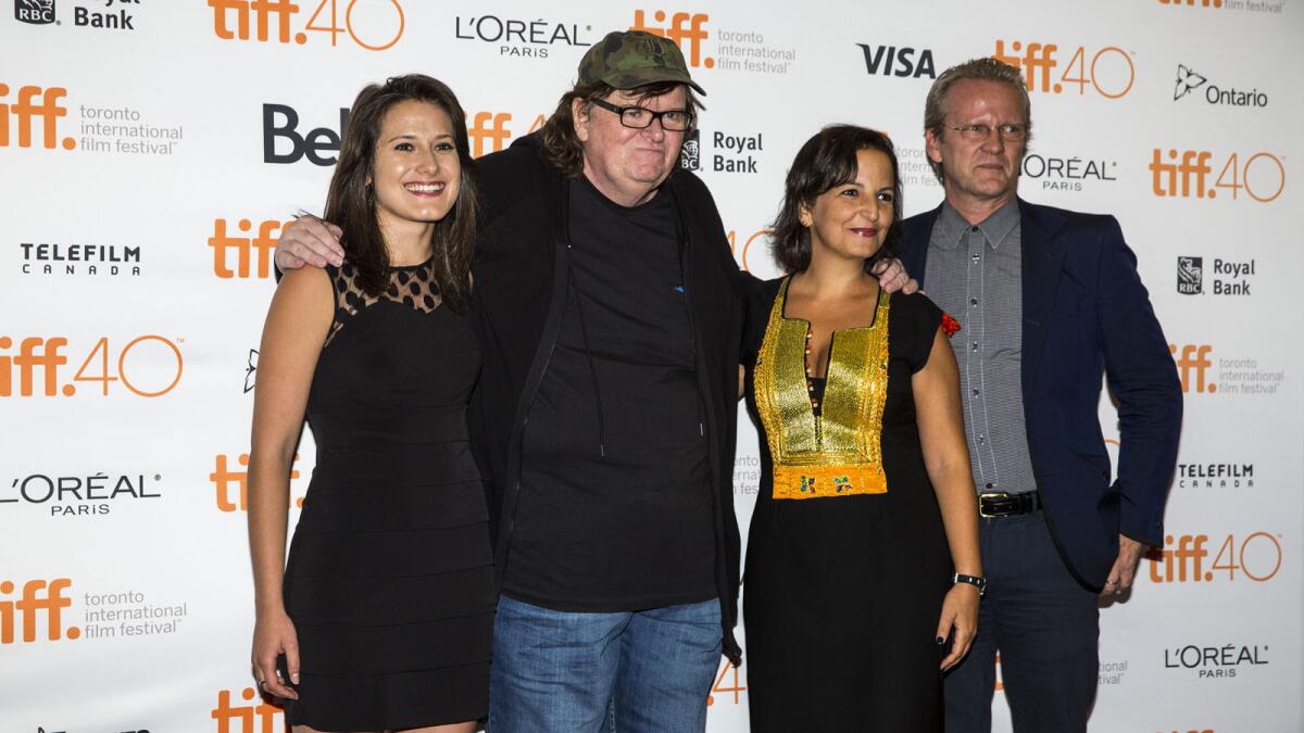 From left, Jenny Tunas, director Michael Moore, Amel Smaoui, and Pasi Sahlberg pose on the red carpet at the world premiere of Moore's latest film, "Where to Invade Next", at the 2015 Toronto International Film Festival.
