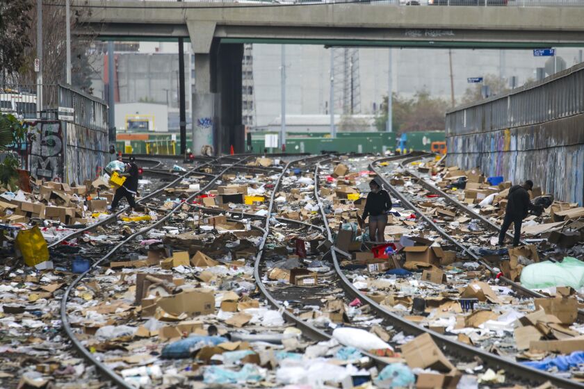 Los Angeles, CA - January 15: People rummaging through stuff stolen from cargo containers littered on Union Pacific train tracks in the vicinity of Mission Blvd. on Saturday, Jan. 15, 2022 in Los Angeles, CA. (Irfan Khan / Irfan Khan)