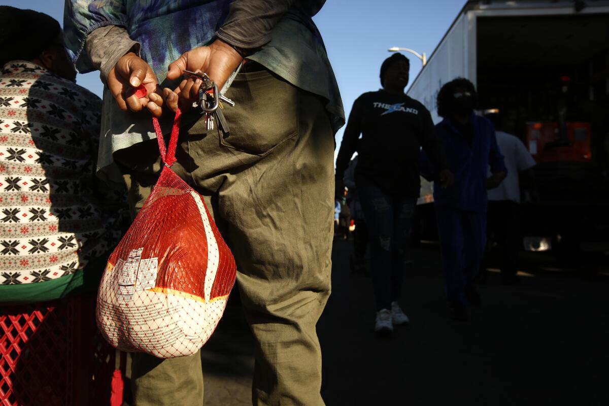 A person holds a free turkey at the 37th Turkey Giveaway in Watts on Nov. 19, 2022.